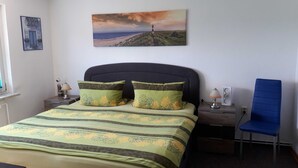 Une chambre à coucher avec un lit, deux oreillers, une table de chevet, une lampe, une chaise et un tableau au mur.