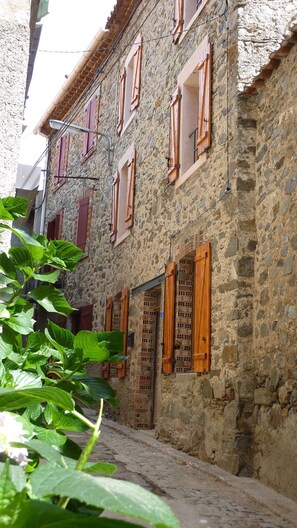 A stone building with wooden shutters and a cobblestone street. - Terrace, large kitchen, WLAN, high quality equipped! Garden 2 min from the house (Berlou)