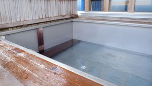 Una habitación con suelo de hormigón, vigas de madera y una ventana con persianas.