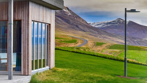 A modern building with large windows and a view of a mountainous landscape. - Wonderful holiday house on the Nollur farm at Eyafjord (Akureyri)