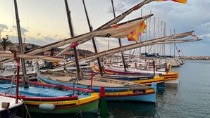 A marina with several colorful boats docked, featuring names like 'Moreneta' and 'Albada'.