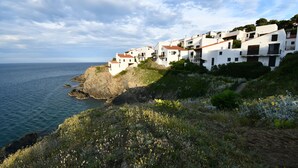 A coastal village with white buildings, a rocky shoreline, and a view of the sea.