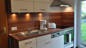 A modern kitchen with white cabinets, a stainless steel sink, a coffee maker, and an oven.