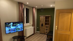 A room with a television mounted on the wall, a wooden cabinet, a door, and a radiator.