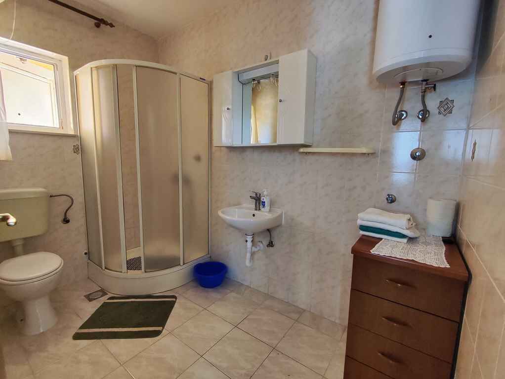 A bathroom with a toilet, shower, sink, and vanity.