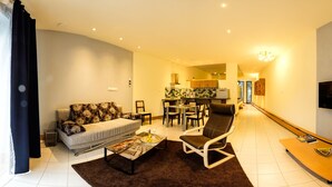 A modern living room with a sofa, coffee table, and a dining area with chairs and a table.