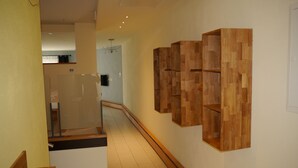 A hallway with wooden paneling on the walls, a tiled floor, and a staircase with wooden steps.