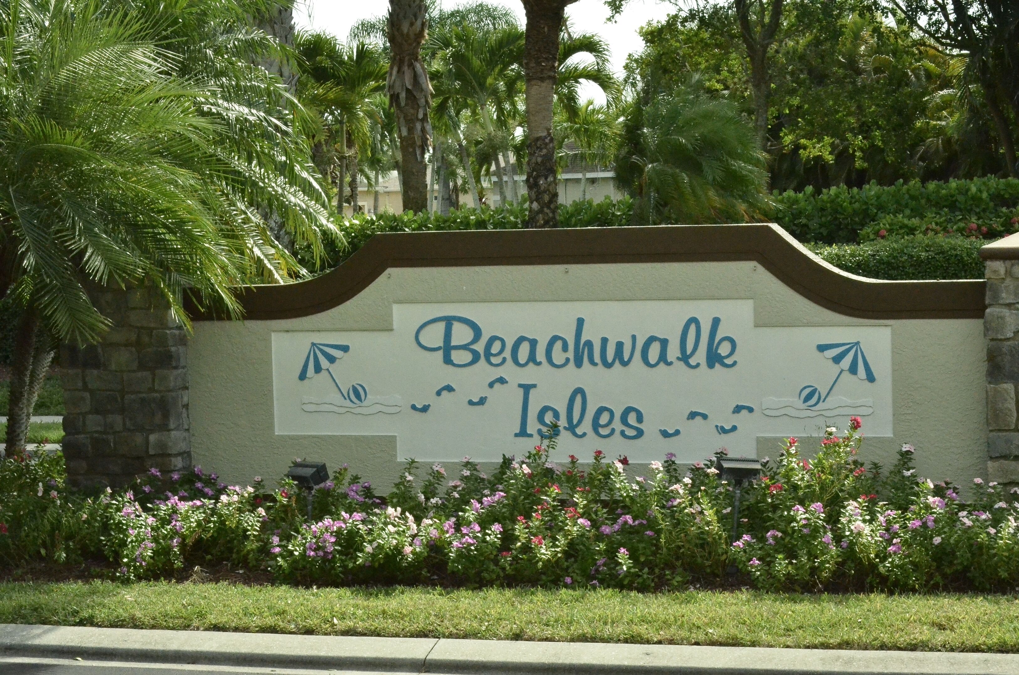 A sign for Beachwalk Isles with palm trees and flowers in the background.