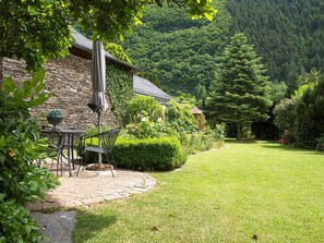 Ein Steinhaus mit Terrasse und Sitzgelegenheit im Freien.