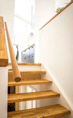 A wooden staircase with a handrail, leading to a room with a wardrobe and a hanging light fixture. - Villa Wanderlust, Mestermann (Reit im Winkl)