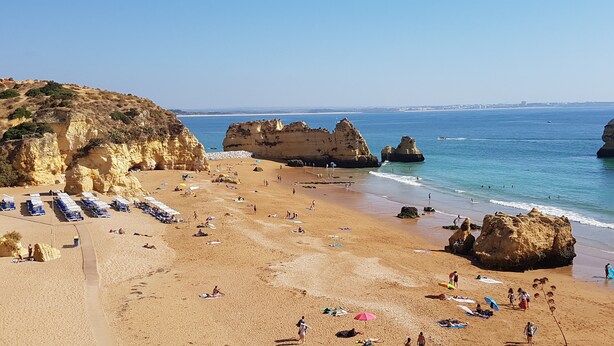 A beach with rocky cliffs, clear blue water, and sunbathers. - Oasis of peace in the Algarve, private pool, heating (Sao Bras de Alportel)