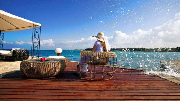 A wooden deck with wicker furniture and a white canopy.