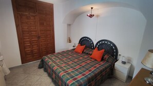 Una camera da letto con un letto, due comodini, un armadio in legno e un lampadario.