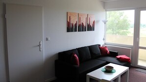 Un saló modern amb un sofà negre, una taula de centre blanca i una finestra gran que ofereix vistes a l'exterior.