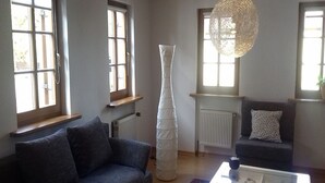 A living room with a sofa, a coffee table, a tall vase, and a hanging light fixture. - Holidays in the idyllic wine-growing village near Freinsheim (Bobenheim am Berg)