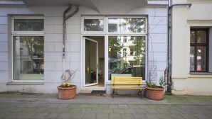 Un edificio con un banco afuera, ventanas amplias y plantas en macetas.