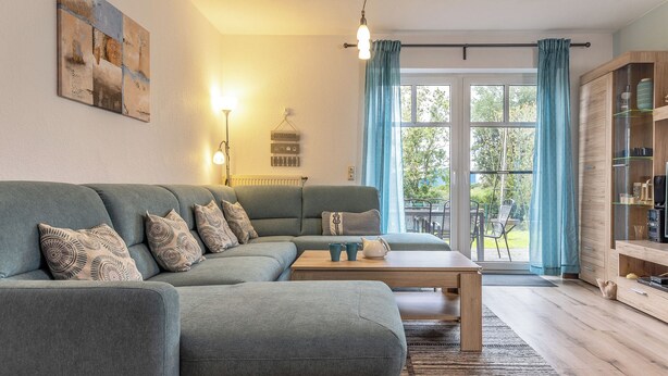 Een moderne woonkamer met een hoekbank, een houten salontafel en een glazen kast.
