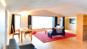 A modern living room with a large window, a red carpet, a wooden dining table, and a black sofa. - Loft house with incredible views of the fjord (Akureyri)