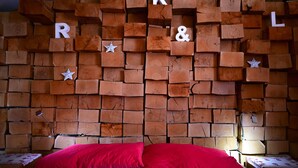A bed with red bedding in a room with a wall made of stacked wooden blocks. - Loft house with incredible views of the fjord (Akureyri)