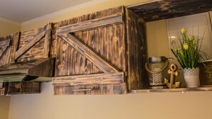 A kitchen with wooden cabinetry and a decorative shelf with a potted plant. - 30sqm vacation apartment close to the beach in the countryside (Stubbenfelde)