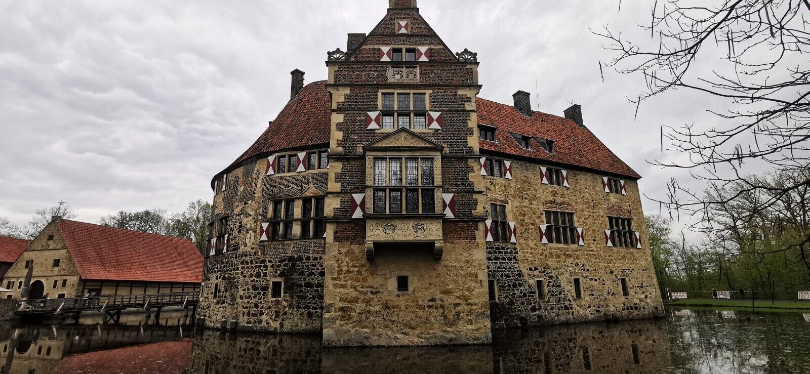 Een historisch gebouw met een gevel van steen, meerdere ramen en een dak met rode dakpannen.