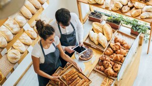 Un comptoir de boulangerie où sont exposés divers produits de boulangerie, et où se trouvent deux employés.
