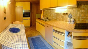 A compact kitchen with yellow cabinets, a microwave, a sink, and a stove. - Holiday home in quiet and sunny location. Perfect for families and friends. (Südtirol)