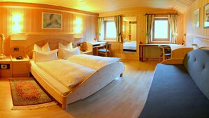 A cozy wooden cabin room with a large bed, a desk, and a comfortable chair. - Holiday home in quiet and sunny location. Perfect for families and friends. (Südtirol)