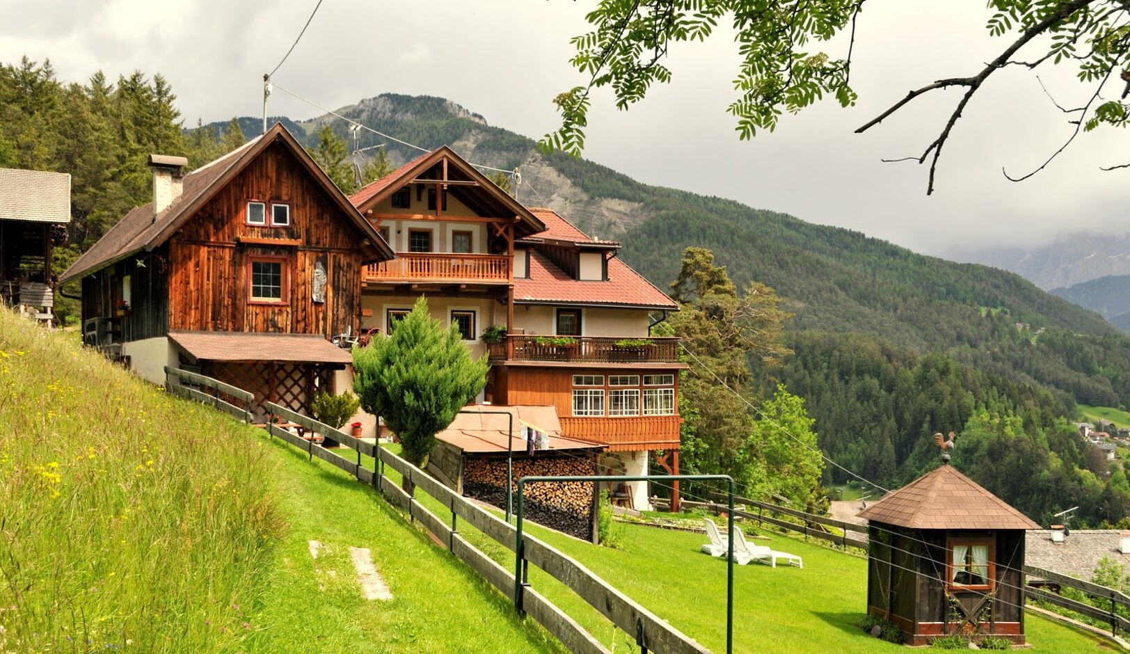 Eine Holzhütte mit einem Balkon vor einer Bergkulisse.