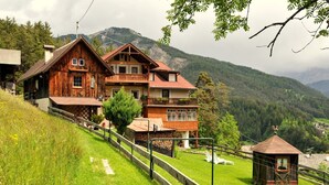 A wooden chalet with a balcony, set against a mountainous backdrop. - Holiday home in quiet and sunny location. Perfect for families and friends. (Südtirol)