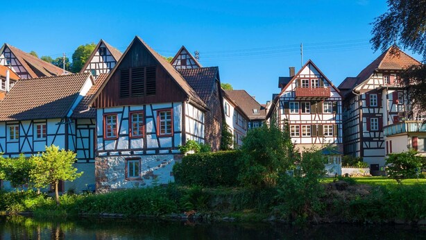 Une maison traditionnelle à colombages, avec une rivière en contrebas.