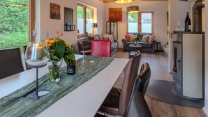 Une cuisine moderne avec des poutres en bois, un coin repas doté d’une table en marbre et un salon chaleureux avec un canapé et une cheminée.