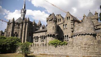 A historic stone castle with multiple towers and a prominent church spire.