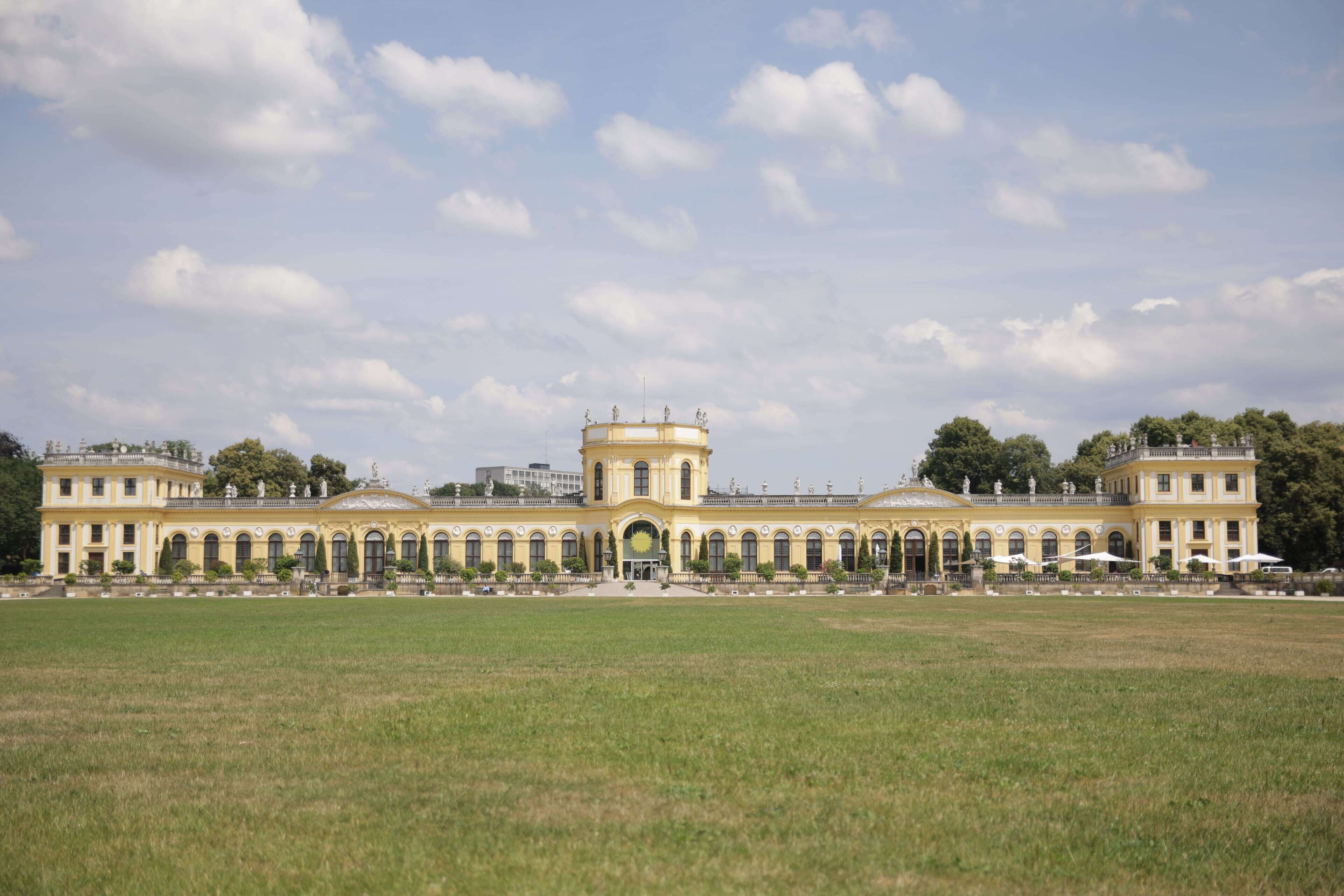 A large, symmetrical building with a central dome and multiple wings, surrounded by a spacious lawn.