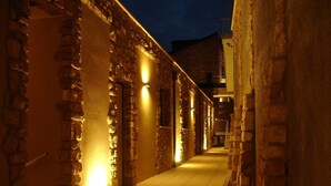 A narrow, stone-walled corridor with evenly spaced lights, leading to a staircase. - Design apartment - 100 sqm green terrace - Pool - Fantastic panoramic lake view (Toscolano-Maderno)
