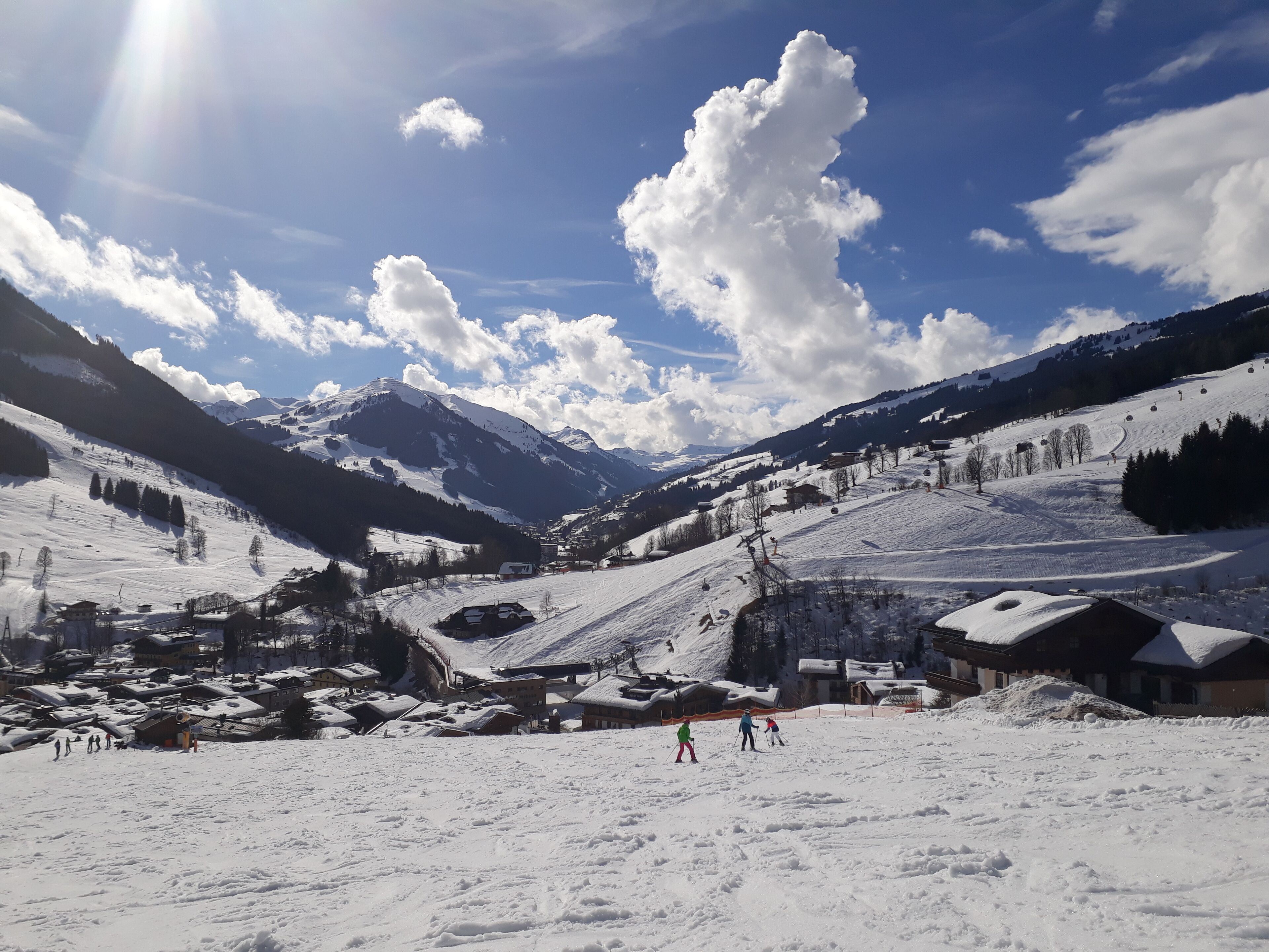 Paisaje nevado de montaña con una estación de esquí, que incluye edificios, pistas de esquí y cielo despejado.