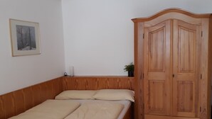 A bedroom with a wooden bed, a wardrobe, and a framed picture on the wall. - Centrally located, newly renovated non-smoking apartment with pool and sauna. (Salzburger Land)