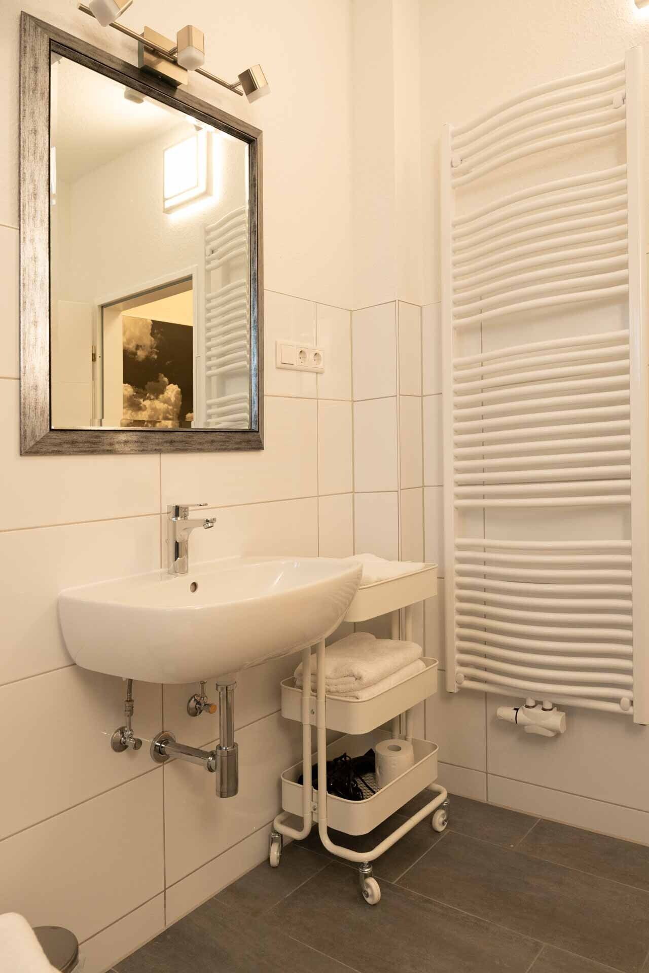 A bathroom with a white sink, a mirror, and a towel rack.