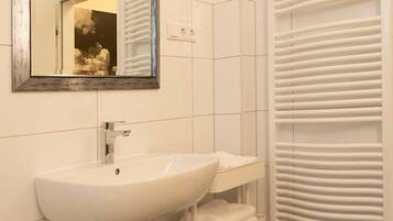 A bathroom with a white sink, a mirror, and a towel rack.