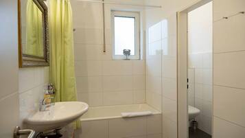 Un baño con un lavamanos blanco, una bañera y un inodoro.