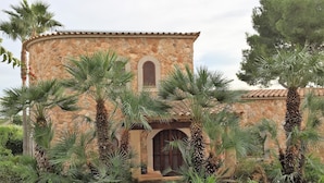 Un bâtiment en pierre avec un coin arrondi, des fenêtres en arc de cercle et un toit recouvert de tuiles.