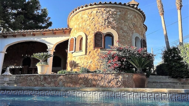 Un bâtiment en pierre doté de fenêtres en arc de cercle et d’une piscine à l’avant.