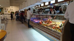 A deli counter with a variety of meats and cheeses, a cash register, and a few customers. - Living room with balcony and sea view, waterfront and south-facing (Vera)