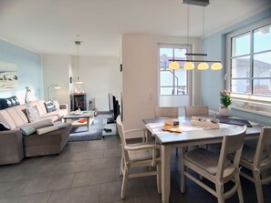 Un salon moderne avec un canapé, une table à manger et des chaises, un téléviseur et une fenêtre donnant sur un beau paysage.