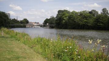 A river with a bridge, greenery, and a building in the background.