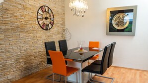 Un espace repas agrémenté d’un mur en pierre, d’un lustre moderne et d’une œuvre d’art encadrée.