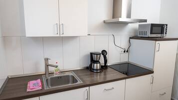 Een moderne keuken met witte kasten, een roestvrijstalen spoelbak, een koffiezetapparaat en een magnetron op een houten aanrecht.