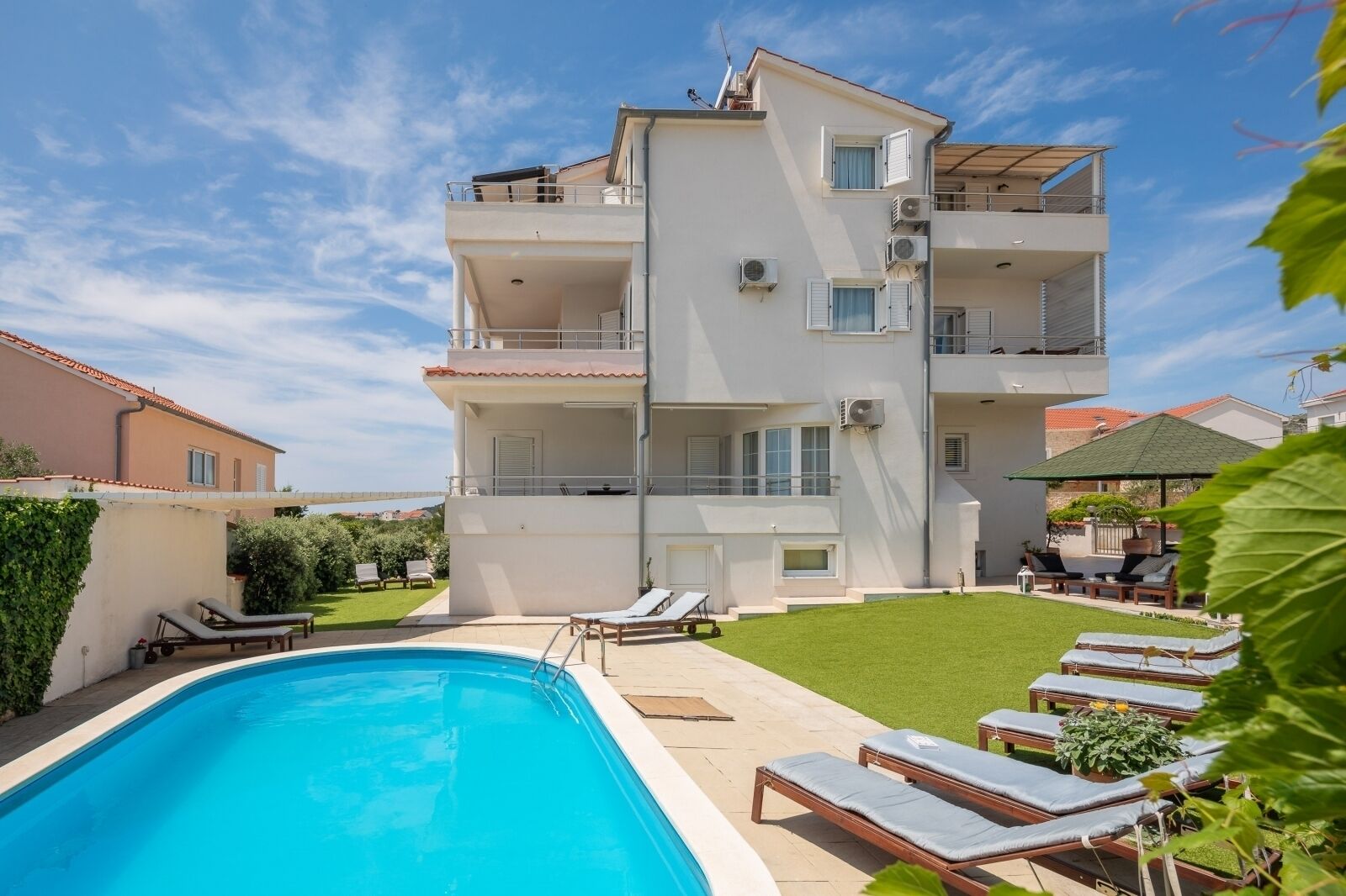 A multi-story building with a swimming pool, outdoor seating, and a well-maintained lawn.