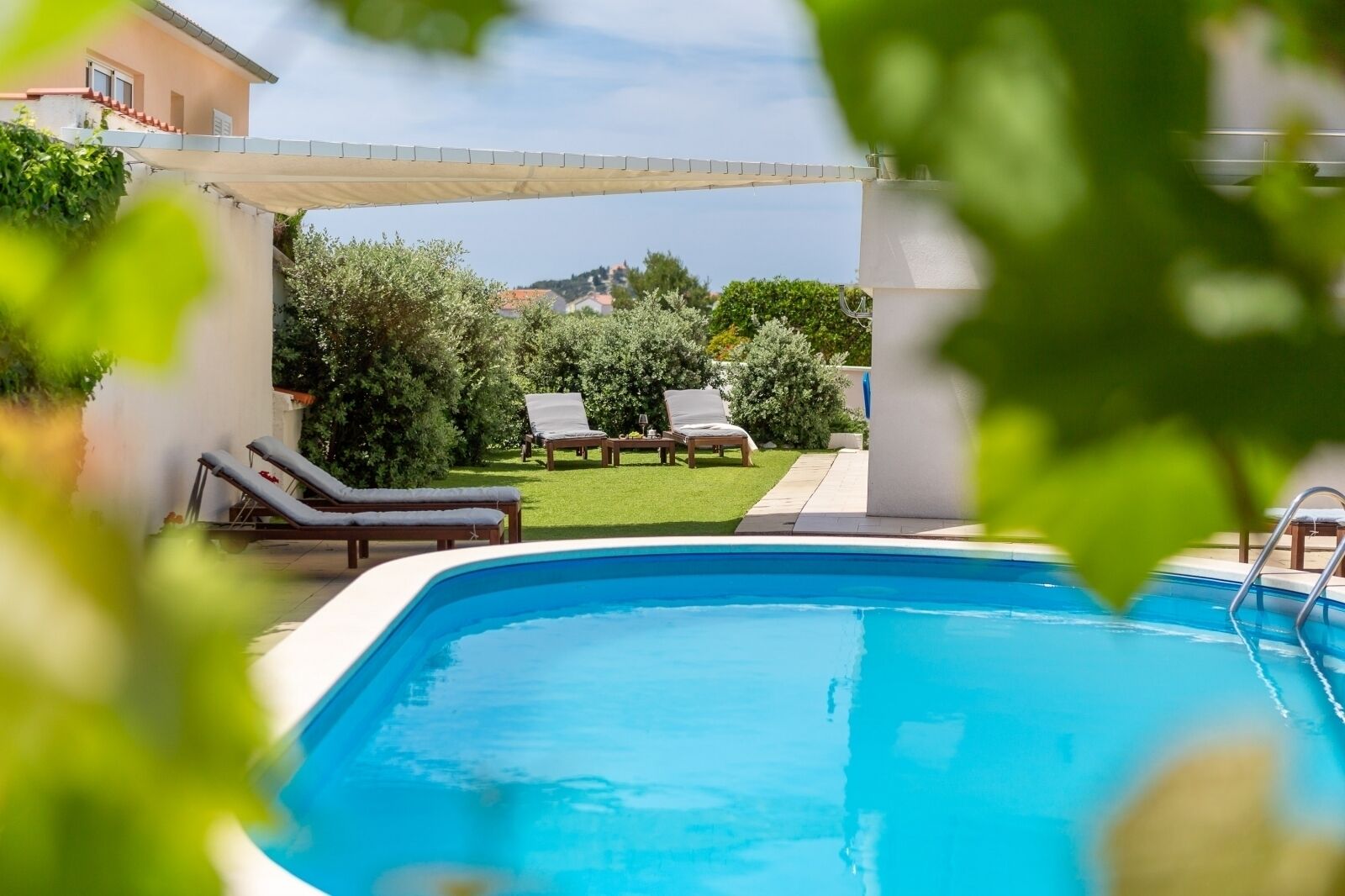A swimming pool with lounge chairs and a covered patio area.