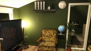 A living room with a television, a floral armchair, a globe, and a mirror. - Centrally located for Harz visitors, fair guests, fitters, Alfeld (5min), Leineberg (Alfeld (Leine))